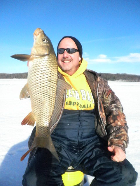 man holding up fish he caught ice fishing