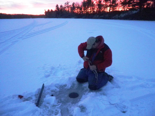 man on frozen lake fishing