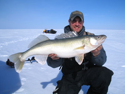 man holding walleye on ice