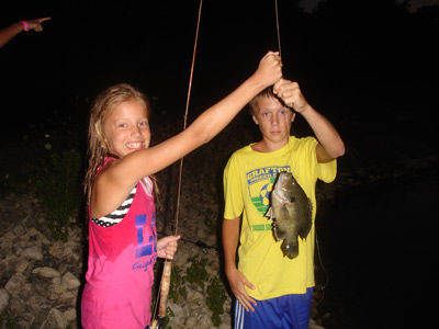 Amanda Luthens hauls in her first fly rod bluegill, with help from resident pond guide Jake Pedersen